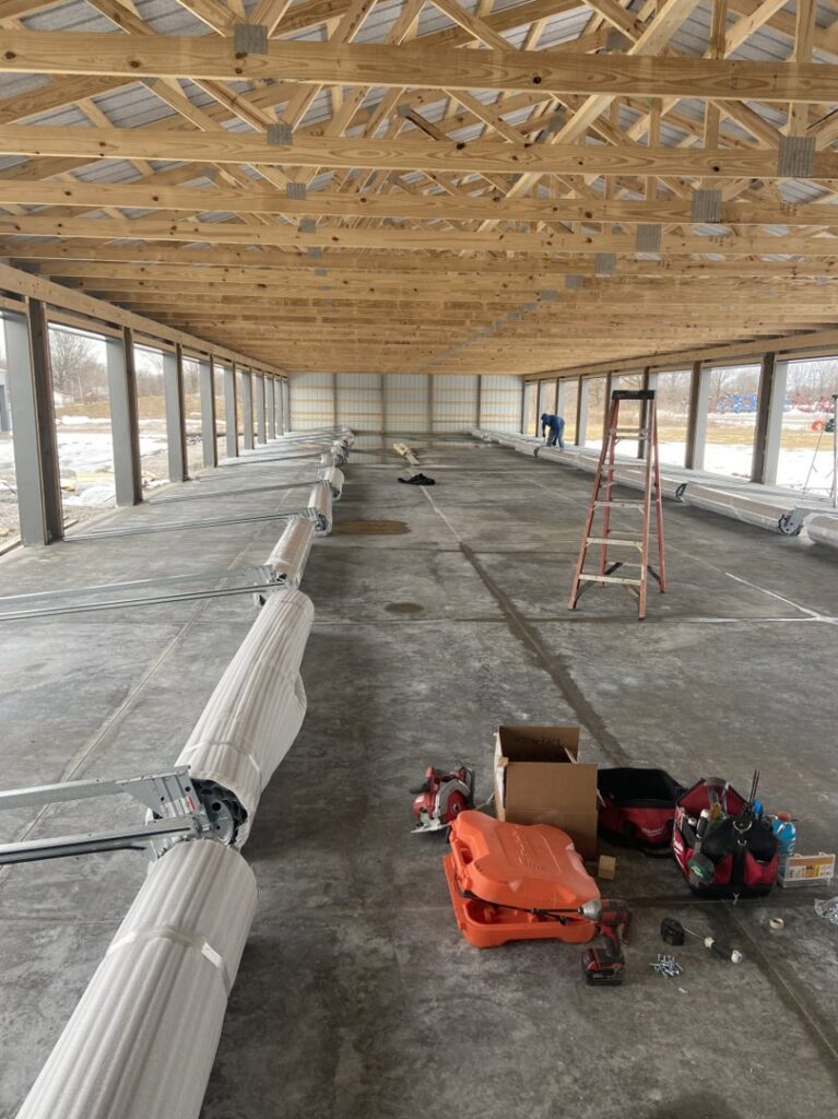 Roll-up garage door components laid out for installation inside a large commercial building by Garage Door Repair Company, LLC in Pueblo, CO.