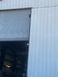 Close-up of a commercial roll-up garage door, partially open, serviced by Horton & Hill Garage Door Specialists LLC in Sapulpa, OK.