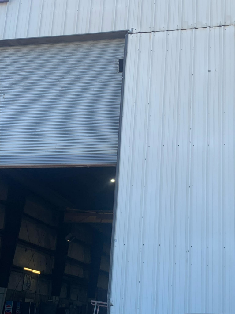 Close-up of a commercial roll-up garage door, partially open, serviced by Horton & Hill Garage Door Specialists LLC in Sapulpa, OK.