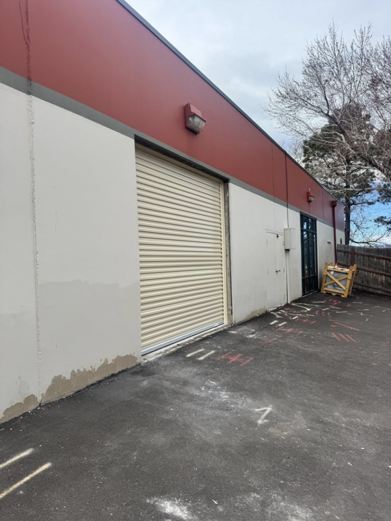 A commercial roll-up garage door on a building exterior during the day, installed by Roll-Rite Garage Doors in Denver, CO.