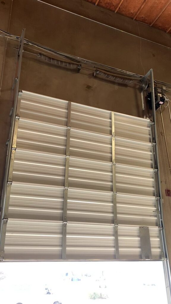 A commercial roll-up style garage door, partially open, installed or serviced by Fix It Now Garage Doors.com in Tempe, AZ.