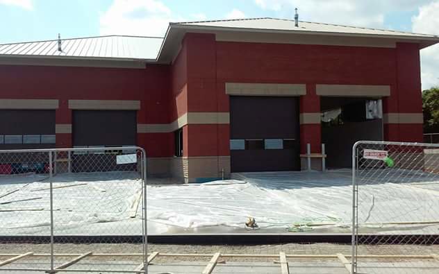 Commercial roll-up garage door installation site with multiple doors and construction fencing by Ken's Overhead Door, Clarksville, TN.