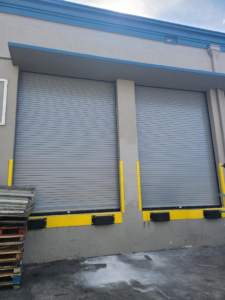 Two grey commercial roll-up garage doors at a loading dock by Hines Garage Doors Service & Repair in Seattle, WA.