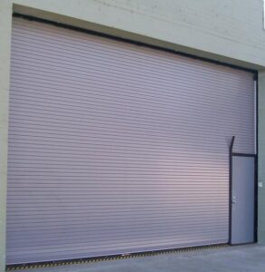 A commercial rolling garage door with an integrated pedestrian door, installed by Overhead Door Company of Maricopa & Pinal County in Mesa, AZ.