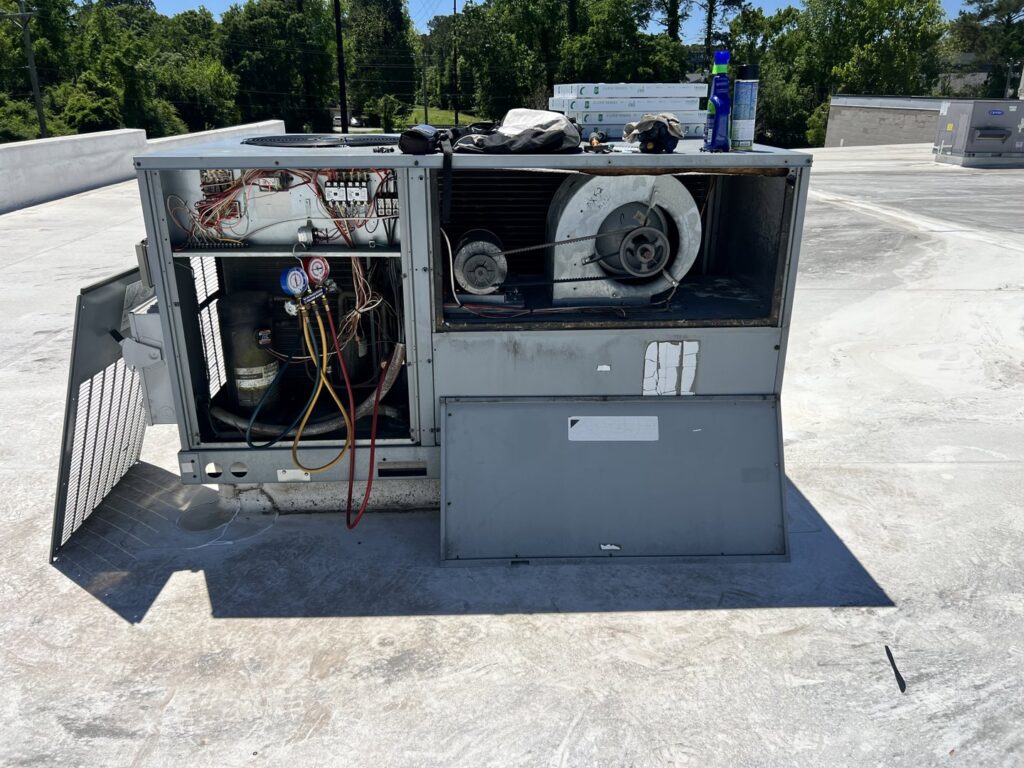 An open commercial rooftop HVAC unit showing internal components and gauges during a repair by Reliable Heating and Air LLC in Summerville, SC.