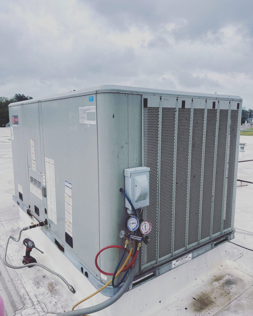 Servicing a commercial rooftop HVAC unit with gauges and tools by A & A Air Conditioning & Heating in Little Rock, AR.