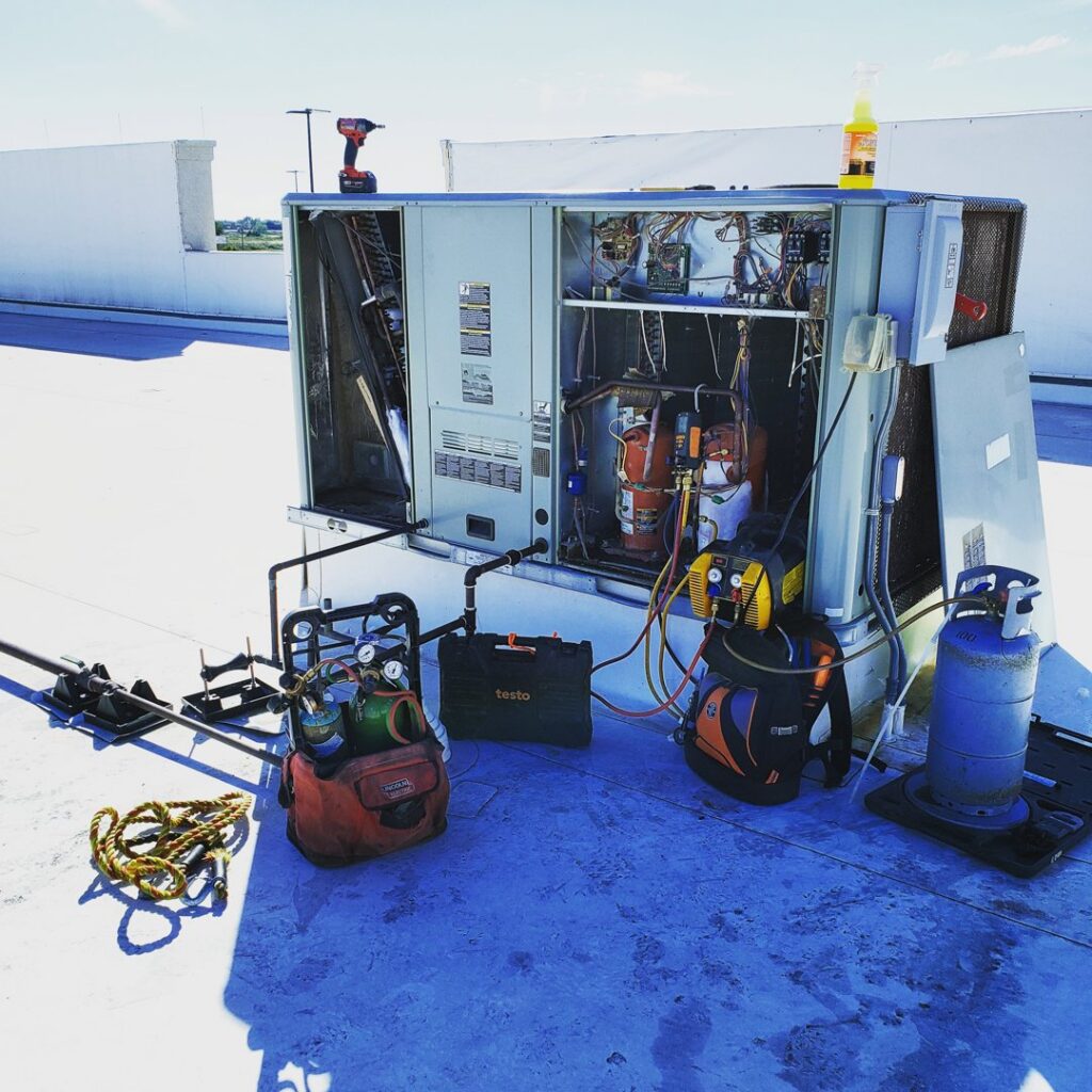 Commercial rooftop HVAC unit undergoing service with tools and equipment by Reading Plumbing, Heating & Air Conditioning in Roswell, NM