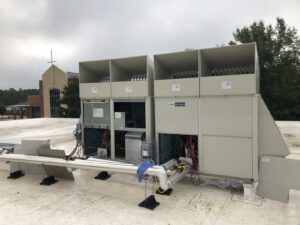 Multiple Mitsubishi commercial HVAC units on a rooftop undergoing service or repair by Deon Arnold Heating & Air Conditioning in Fayetteville, NC