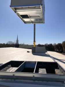 A commercial rooftop HVAC unit being lifted by a crane for installation by Crouch's Heating & Cooling LLC in Stillwater, OK.