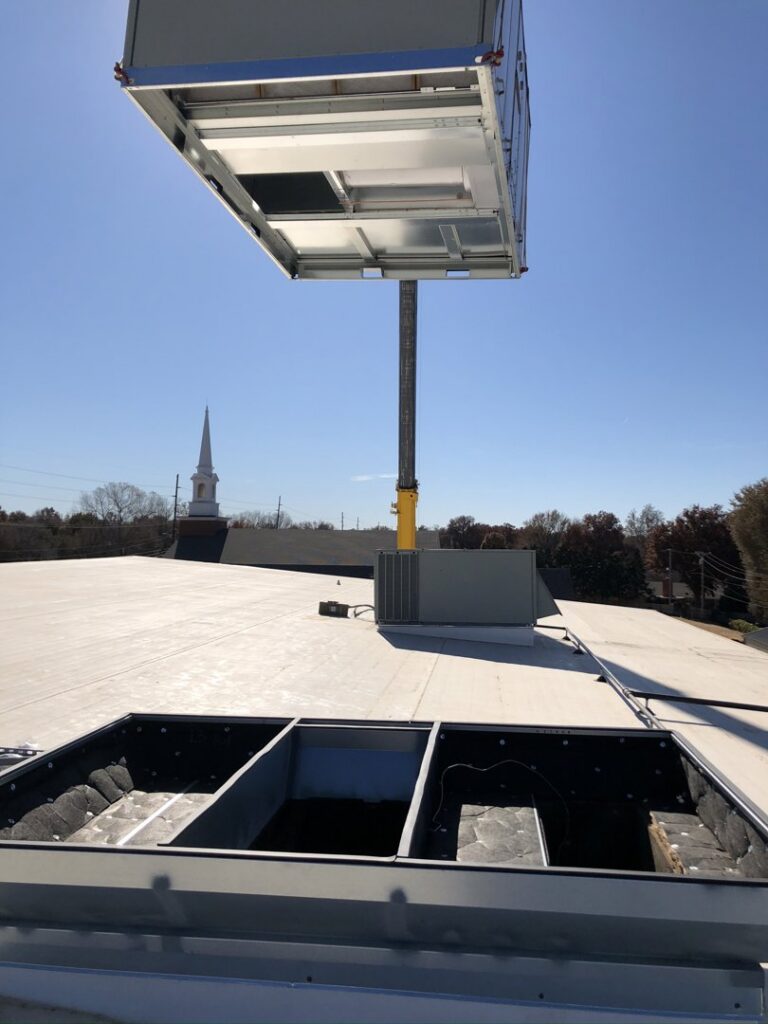 A commercial rooftop HVAC unit being lifted by a crane for installation by Crouch's Heating & Cooling LLC in Stillwater, OK.