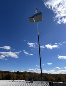 A large commercial rooftop HVAC unit being lifted by a crane for installation by DND Mechanical in Columbus, OH.