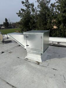 A commercial rooftop HVAC unit and ductwork on a building by DeHart Plumbing, Heating, & Air in Sparks, NV.