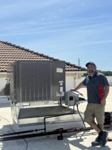 A technician standing next to a commercial rooftop HVAC unit installed by G.M. AIR Conditioning & Heating in Wichita, KS.
