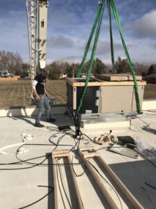 Commercial rooftop HVAC unit installation by crane with technician from A-1 Heating and Air Conditioning Service in Alexandria, VA
