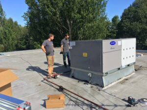 Technicians installing a commercial rooftop HVAC unit for The Heating Specialist in Portland, OR