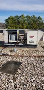 A commercial rooftop HVAC unit with an access panel open, showing internal components, serviced by A1 Mechanical Heating and Cooling Services in Waynesville, OH.