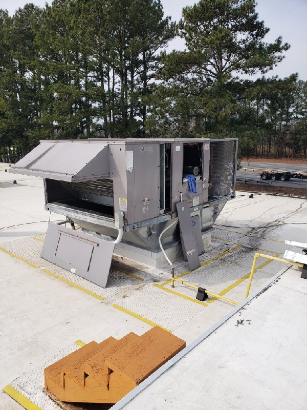 A commercial rooftop HVAC unit with access panels open for service by SBS-NC, LLC in High Point, NC