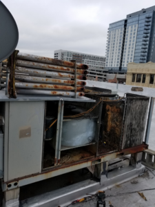 A large, rusted commercial rooftop HVAC unit undergoing repair or maintenance by ARC Mechanical Inc in South Elgin, IL.