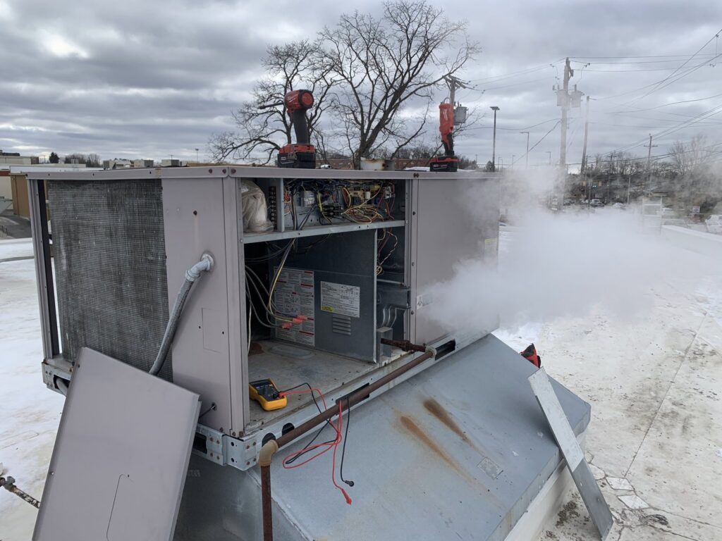 A commercial rooftop HVAC unit emitting smoke or steam during a repair by PureAir HVAC in Bel Air, MD.