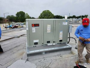 A technician services a large commercial rooftop HVAC unit for BV Air Conditioning & Heating in Dallas, TX.
