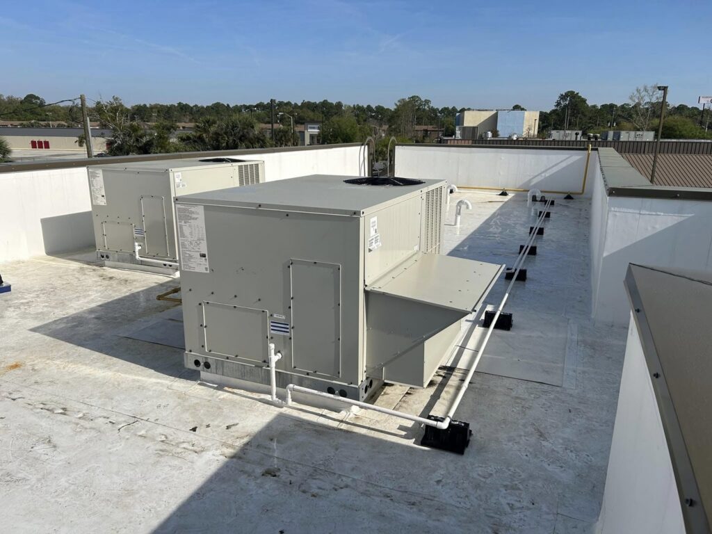 Two commercial rooftop HVAC units installed on a white roof by Huggins Mechanical in Jacksonville, FL