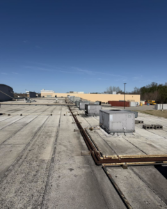 Multiple commercial rooftop HVAC units visible on a large building, serviced by Mission HVAC in Huntsville, AL.