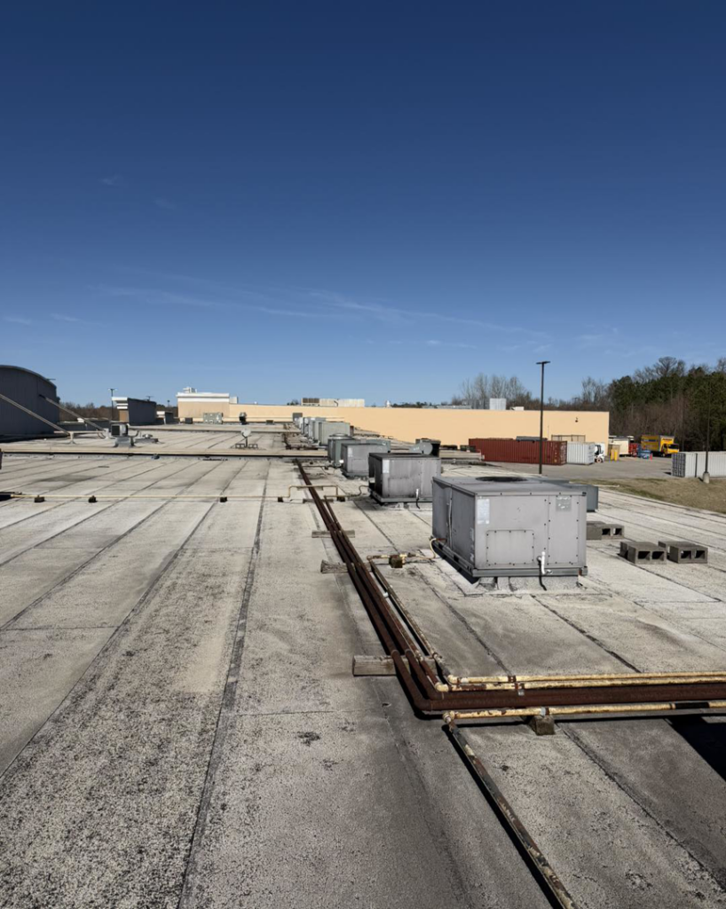 Multiple commercial rooftop HVAC units visible on a large building, serviced by Mission HVAC in Huntsville, AL.