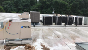 Commercial rooftop HVAC units, with one being serviced, by Leidigh's Heating & Air Conditioning in Marysville, PA.