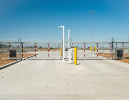 A commercial security gate with barbed wire and surveillance cameras installed by Competitive Fence Contractors LLC in Scottsdale, AZ.