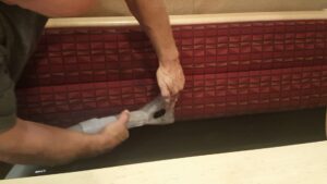 A professional cleaning commercial upholstery bench seating with a specialized tool at Believe That Carpets & Upholstery Cleaning in Colorado Springs, CO.