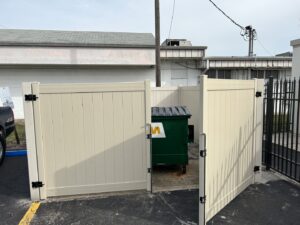 A commercial beige vinyl fence enclosure for a dumpster, installed by Florida Professional Fence LLC in Altamonte Springs, FL.