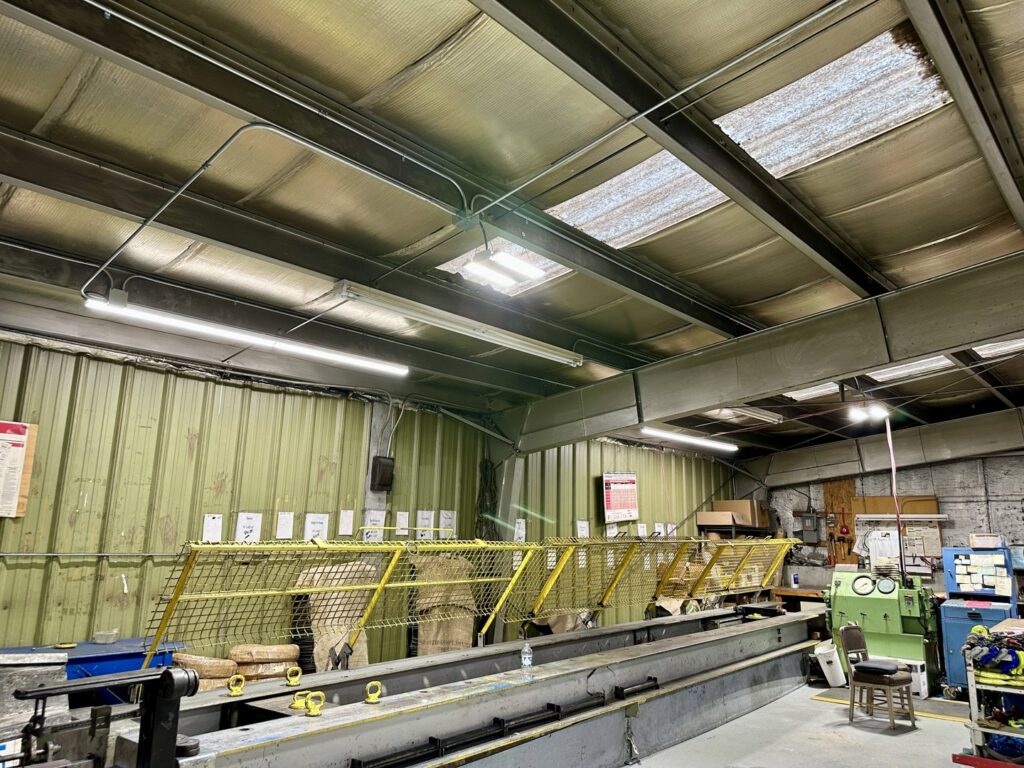 Overhead fluorescent lighting and conduit installed in a commercial warehouse by Lighten Up Electric, LLC in Cranston, RI.