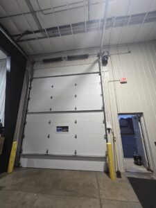 A large commercial white garage door with its overhead mechanism installed by LabraDoor Overhead Services in Eau Claire, WI.