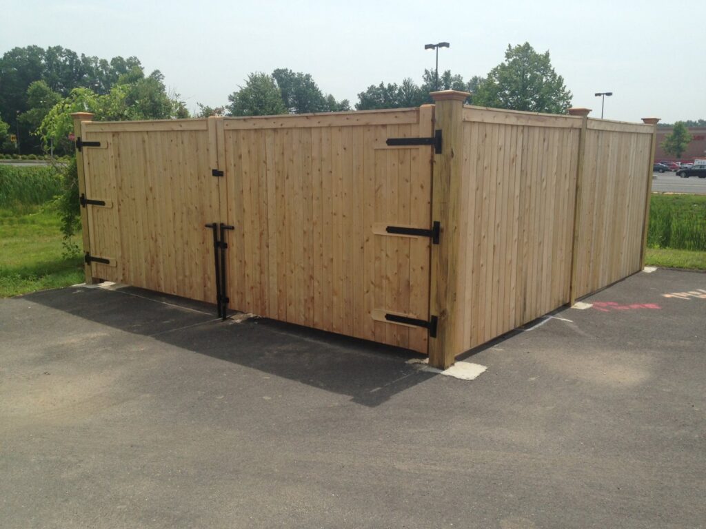 A commercial wooden privacy fence with double gates, installed by Brodeur-Campbell Fence Co. in Springfield, MA, for a utility enclosure.