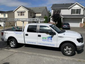 A company service truck for ETS - Garage Door & Electric Gate Repair Of Bellevue, WA, parked in a residential neighborhood.