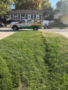 A Nebraska Pro Turf & Pro Pest Solutions company truck parked on a residential street next to a lawn with a service sign in Omaha, NE.