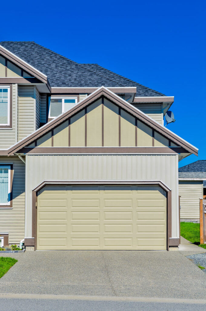 An Ozarks Overhead Door & More company truck parked at a job site with a newly installed gray garage door in Springfield, MO.
