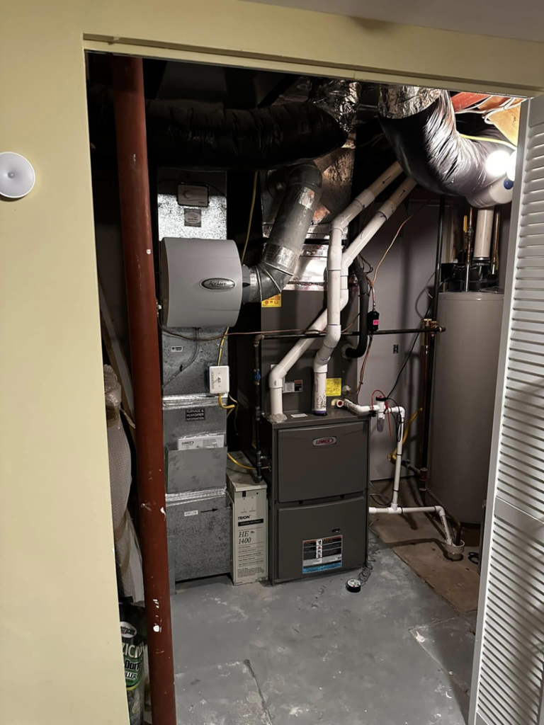 A complete HVAC system including a furnace, air handler, humidifier, and water heater in a utility closet by Adonis Hvac in Annapolis, MD.