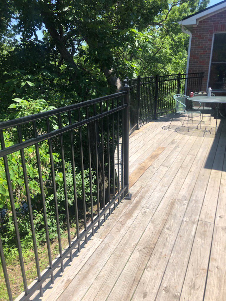 A section of completed black metal railing on a wooden deck installed by Van's Fence in Kansas City, MO.