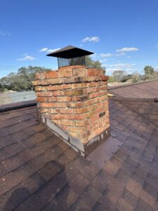 A newly repaired brick chimney with fresh flashing on a residential roof by Lone Star Chimney in Houston, TX.