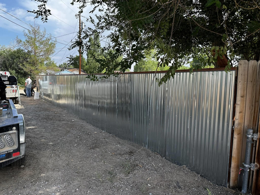 A completed corrugated metal fence installation with a work truck nearby by Tomahawk Fencing in Riverton, WY.