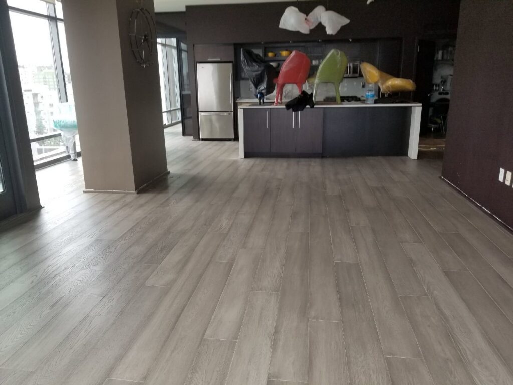 A spacious room with newly installed grey wood-look plank flooring, a completed project by LACarpetWarehouse in Los Angeles, CA.