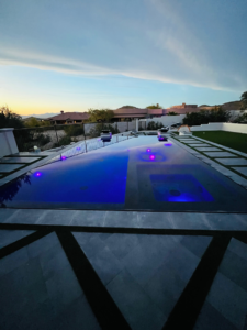 A stunning completed infinity-edge pool with purple lights at dusk by SoCal Pool Construction LLC in Scottsdale, AZ.