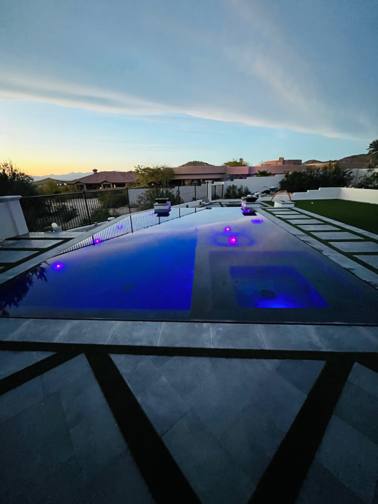 A stunning completed infinity-edge pool with purple lights at dusk by SoCal Pool Construction LLC in Scottsdale, AZ.