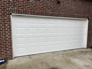 A completed installation of a white panel garage door on a brick residence by J&S Garage Door Services in Franklin, TN.