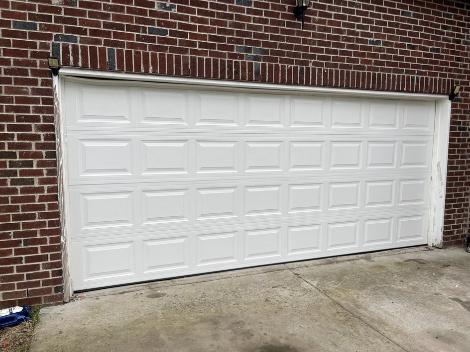 A completed installation of a white panel garage door on a brick residence by J&S Garage Door Services in Franklin, TN.