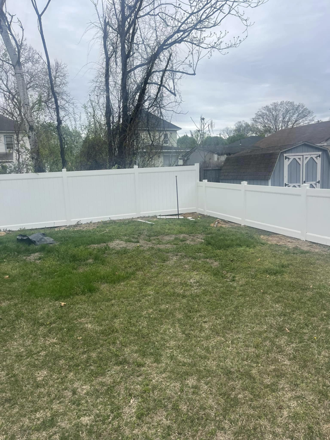 A newly completed white vinyl privacy fence in a residential backyard by Fence Pros LLC in Medford, OR.