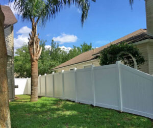 A newly installed white vinyl privacy fence enclosing a residential backyard by Julien Affordable Fencing LLC in Jacksonville, FL