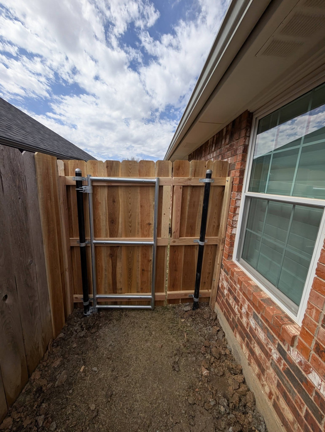 A completed wood and metal gate installation by Black and Sons fencing in Indiahoma, OK, in a side yard.