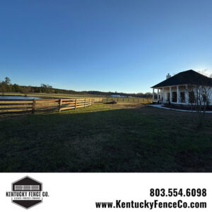 A long view of a completed wooden fence surrounding a property with a house and pond by Kentucky Fence Co in McConnells, SC.